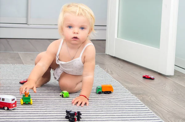 Loira bebê menina jogar brinquedo carros em casa — Fotografia de Stock