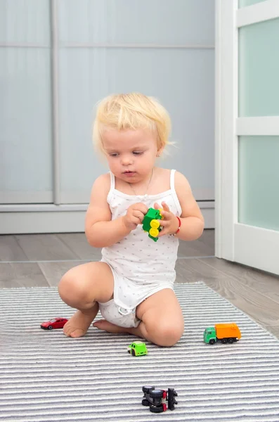 Loira bebê menina jogar brinquedo carros em casa — Fotografia de Stock