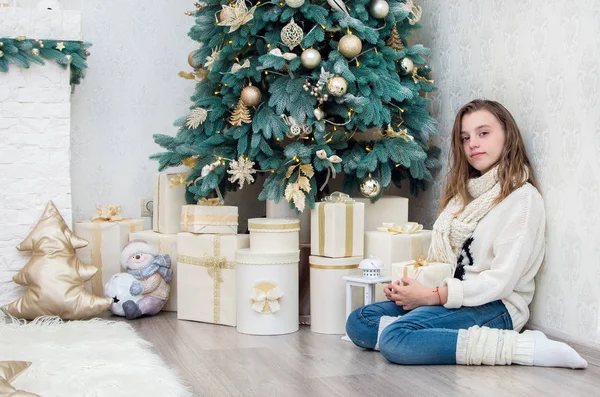 Chica adolescente con un regalo en sus manos agachado al lado de la decoración —  Fotos de Stock