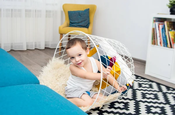 Menino engraçado jogando em casa com uma cesta, subiu para dentro — Fotografia de Stock