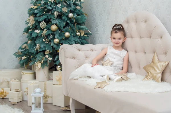 Drăguț fetiță în rochie albă, crouched pe canapea — Fotografie, imagine de stoc