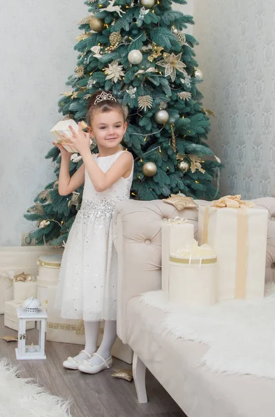 Drăguț fetiță în rochie albă care deține un cadou în Ajunul Crăciunului — Fotografie, imagine de stoc