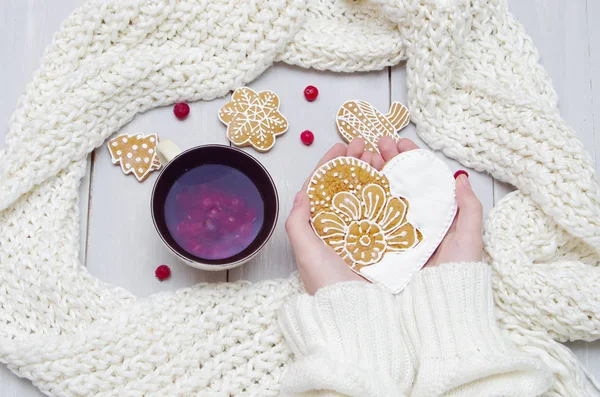 Hände in einem Pullover mit einer Tasse Tee und einem Keks auf einem hölzernen — Stockfoto