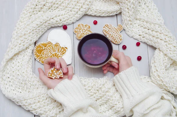 Hände in einem Pullover mit einer Tasse Tee und einem Keks — Stockfoto