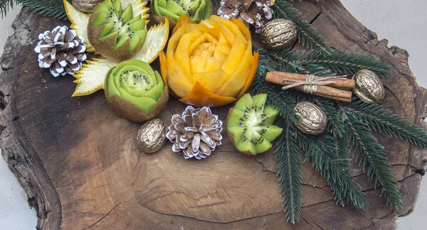 Composition of fresh carved fruits decorated with fir branches — Stock Photo, Image