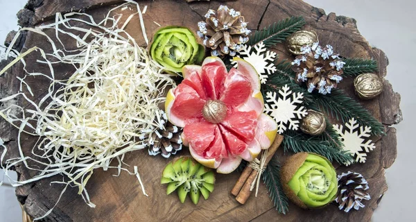 Composition of fresh carved fruits decorated with fir branches — Stock Photo, Image