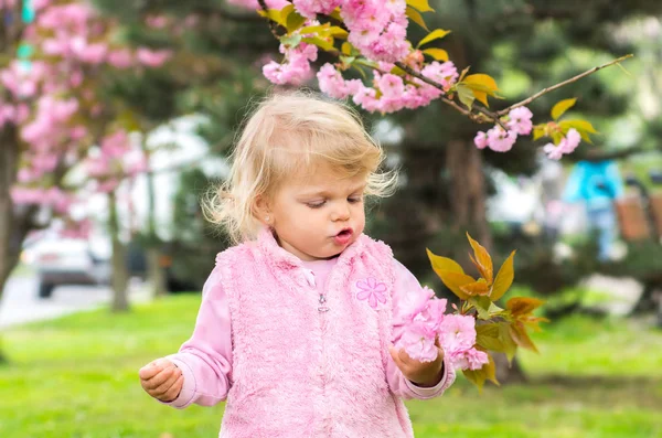 Little charming blonde playing with pleasure in the garden — Stock Photo, Image