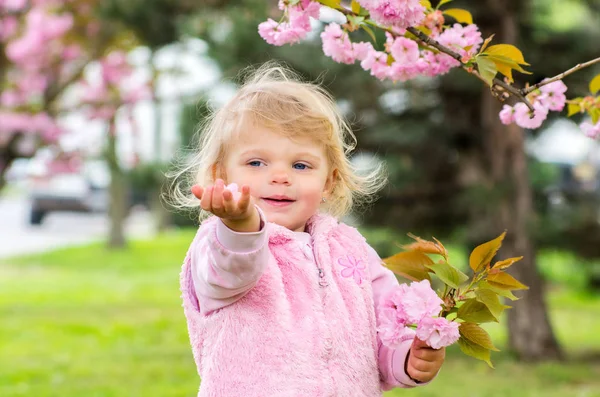 Маленькая очаровательная блондинка играет с удовольствием в саду с — стоковое фото