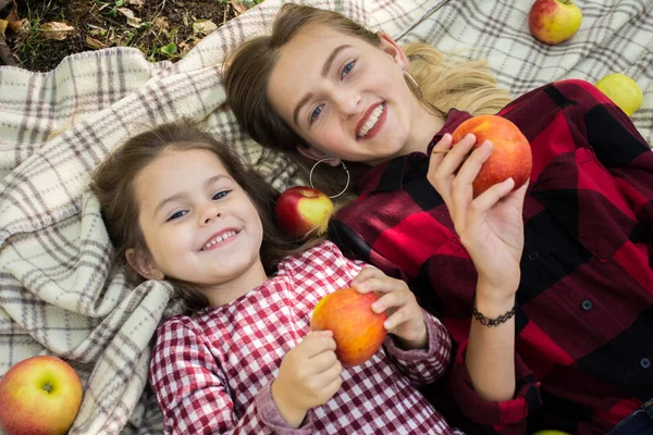 Две сестры в клетчатом платье едят яблоки — стоковое фото