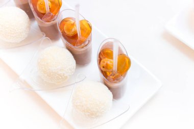 Gurme karamel fındıklı tatlılar fincanlarda ve hindistan cevizli şekerler bir tabakta