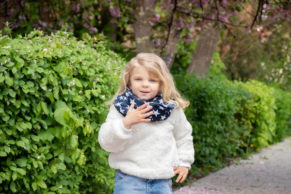Portrait of a blue-eyed little blond girl on a background of nature in a scarf with stars
