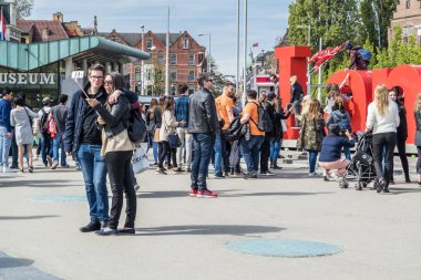 Amsterdam, Hollanda - 31 Nisan 2017: Çift alarak selfies ederken ben Amsterdam mektup müzenin zaman atlamalı önünde kare içinde dolaşan insanlar
