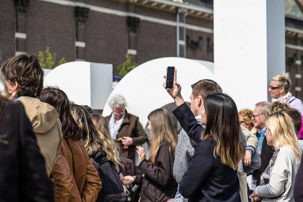 Amsterdam , Netherlands - April 31, 2017 : Asian lady taking selfies while people walking around in the streets