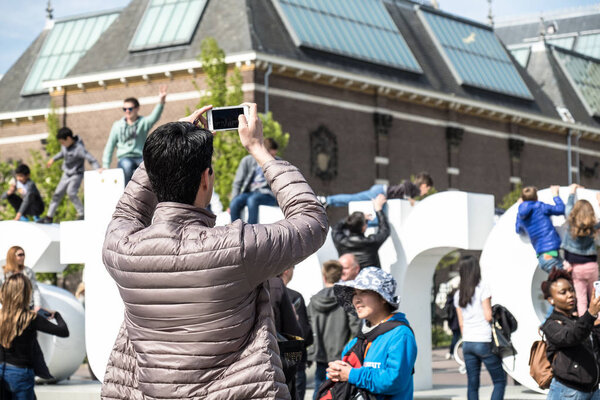 Amsterdam , Netherlands - April 31, 2017 : Man taking selfies while people walking around in the streets