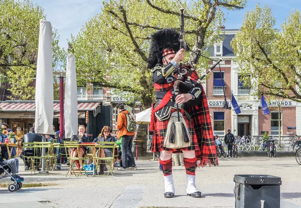 Amsterdam, Países Bajos - 31 de abril de 2017: gaitero escocés afinando su instrumento en las calles de Ámsterdam con su tartán Royal Stuart — Foto de Stock
