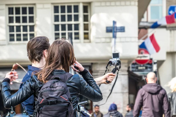 Amsterdam, Holandia - 31 kwietnia 2017 r.: Para biorąc selfie, podczas gdy ludzie chodzą na ulicach Amsterdamu — Zdjęcie stockowe