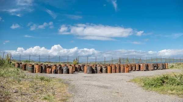 Rusty fuel and oil casks stored at an fence