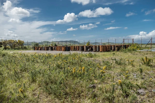 Rusty fuel and oil casks stored at an fence