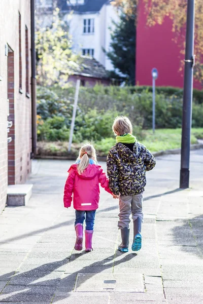 Hermano y hermana caminando de la mano en la ciudad — Foto de Stock