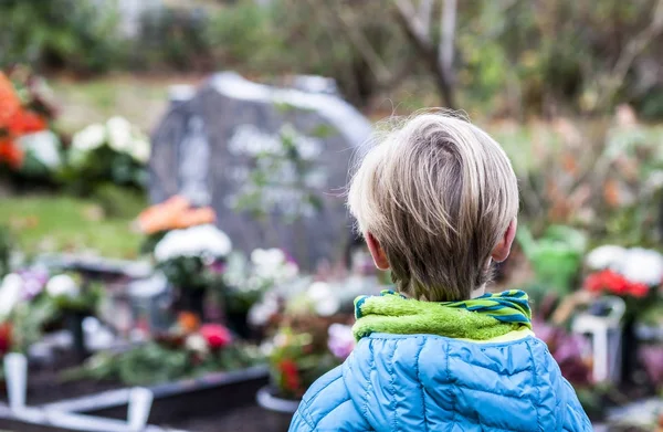 Kleiner Junge steht am Grab seiner Eltern — Stockfoto
