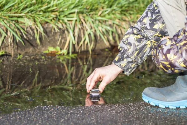 Petit garçon en bottes en caoutchouc coloré jouant avec sa voiture jouet dans la flaque d'eau — Photo