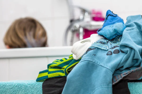Одежда на переднем плане в то время как маленький мальчик в ванной — стоковое фото