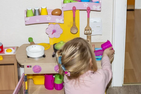 Klein meisje koken in de speelgoed keuken — Stockfoto