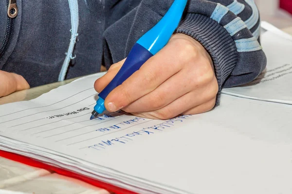 Left handed young doing his homework - Translation: should, can, want, swimming, the word with rr — Stock Photo, Image