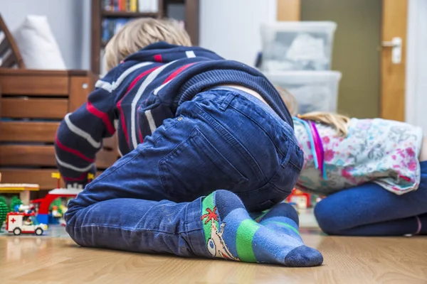 Двое маленьких детей играют с кирпичами на полу — стоковое фото