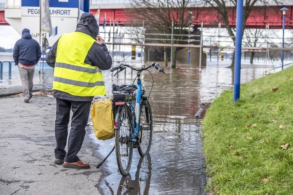 Duisburg, Alemanha - 08 de janeiro de 2017: motorista de bicicleta surpreso com o rio Reno inundando o passeio em Ruhrort — Fotografia de Stock