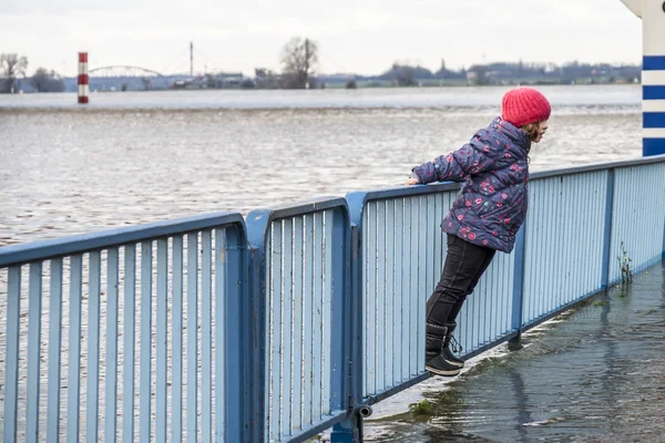 Duisburg, Tyskland - januari 08 2017: Liten flicka förvånad vid floden Rhen översvämningar strandpromenaden — Stockfoto