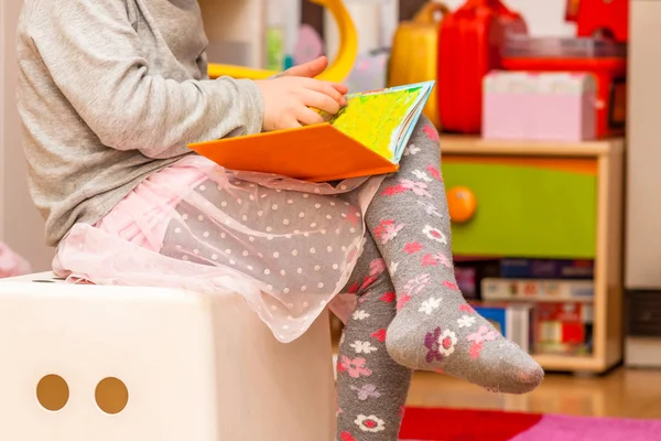 Маленькая девочка читает красочную книгу — стоковое фото