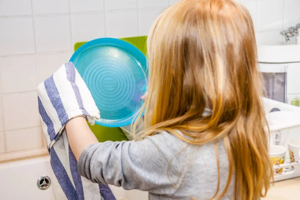 Дівчина на кухні з тарілкою і рушником в руці біля раковини — стокове фото