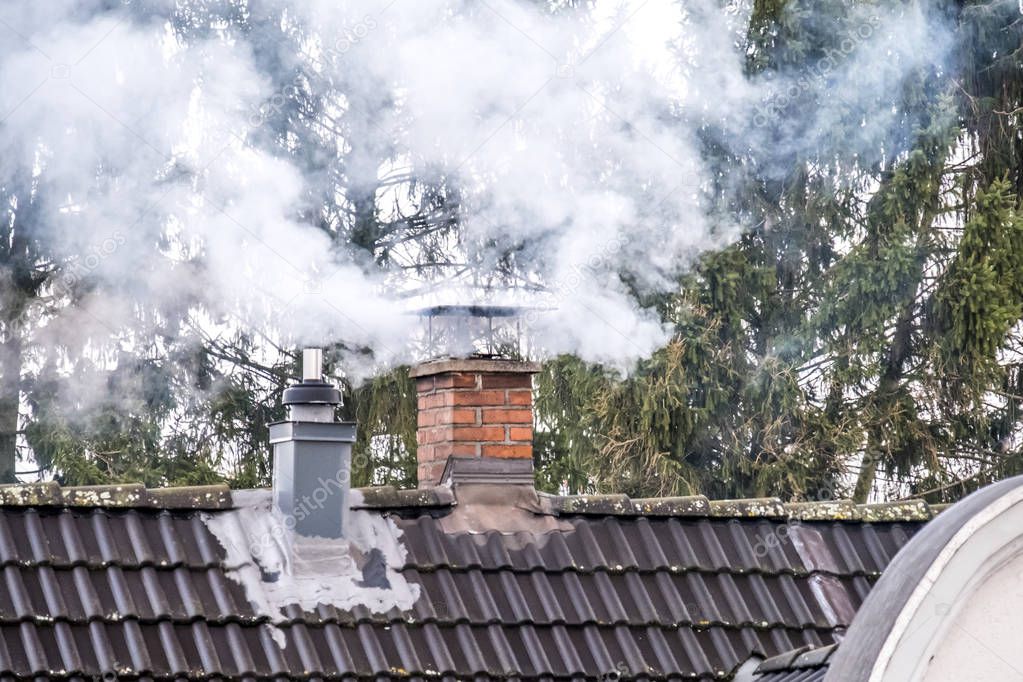 Smoking chimney and pipe on the top of a house