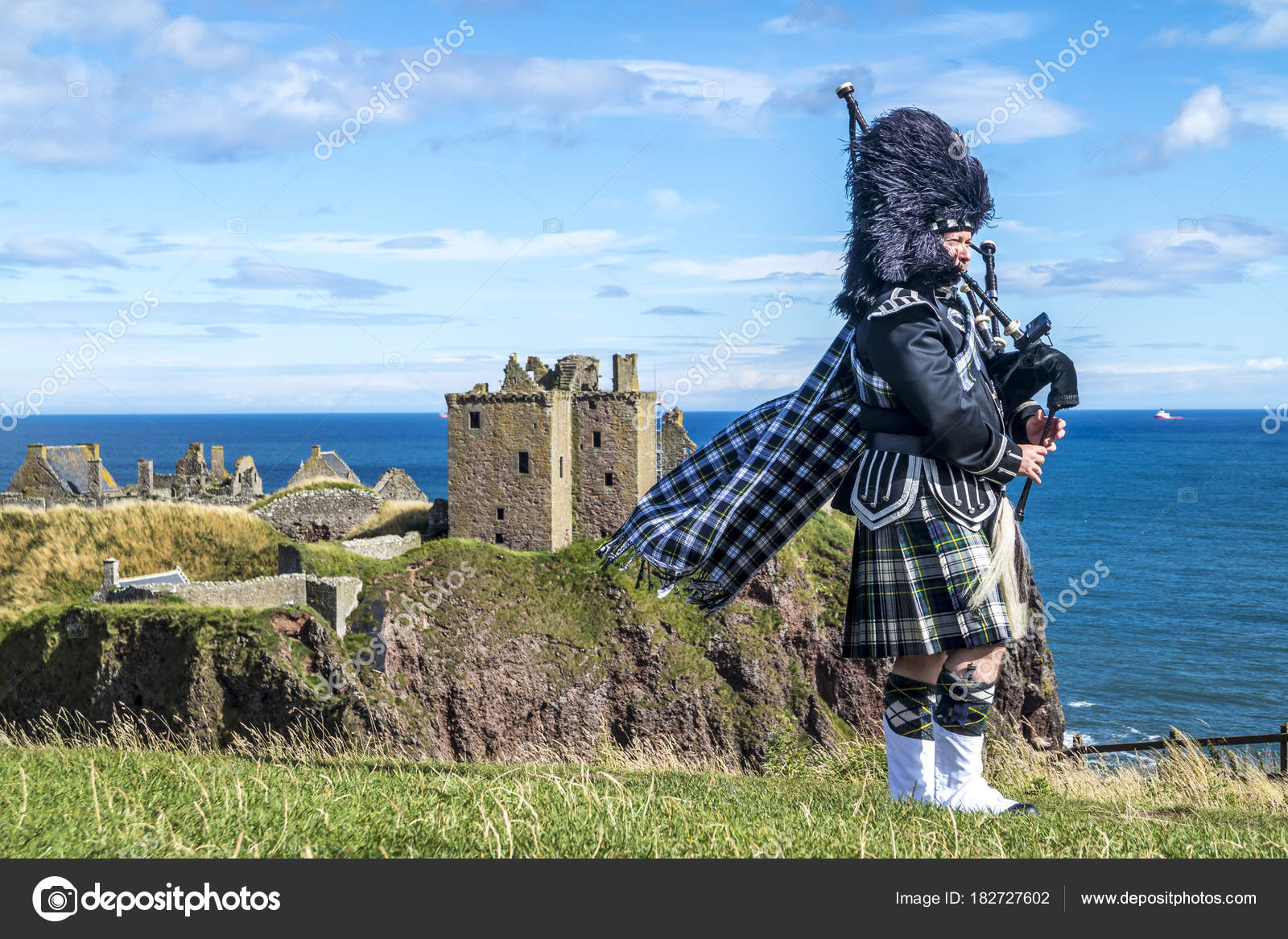 Traditional scottish bagpiper in full dress code at Dunnottar Castle in ...