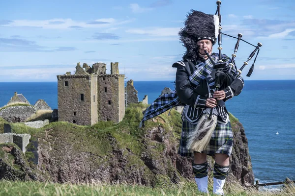 Traditional scottish bagpiper in full dress code at Dunnottar Castle in Stonehaven — Stock Photo, Image