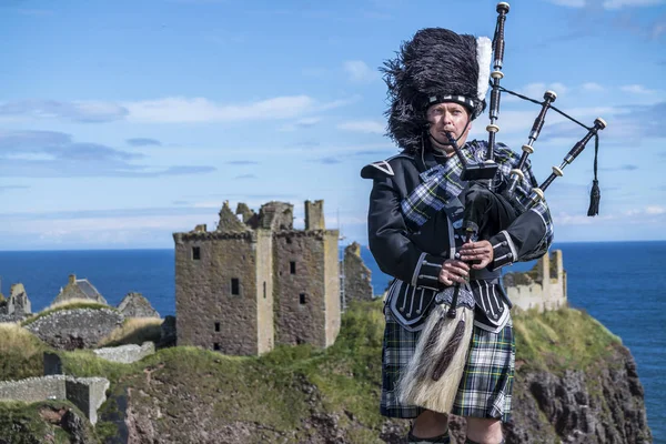 Traditional scottish bagpiper in full dress code at Dunnottar Castle in Stonehaven — Stock Photo, Image