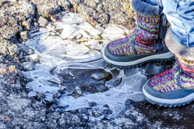 Child stands on icy dirty puddle clipart