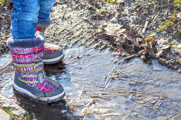 Çocuk buzlu kirli su birikintisi üzerinde duruyor