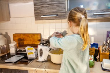 Küçük kız mutfakta bir tarifi smartphone üzerinde takip waffle pişirme