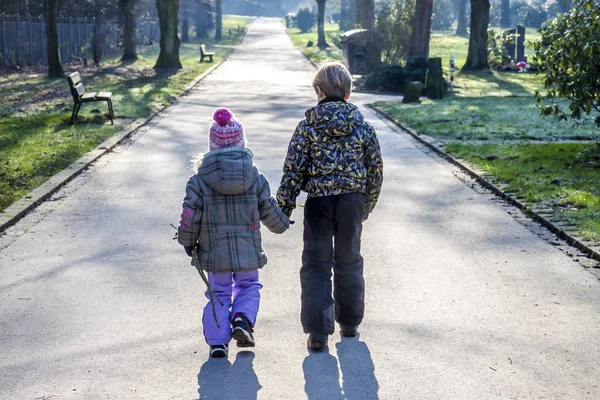 Menino e menina de mãos dadas e caminhando por um longo caminho reto — Fotografia de Stock