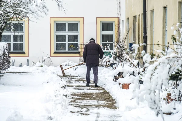 Человек убирает снег с тротуара — стоковое фото