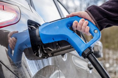 Bir elektrikli araba şarj ve arka planda bir araba kısmi bir görünümü
