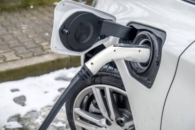 Bir elektrikli araba şarj ve arka planda bir araba kısmi bir görünümü