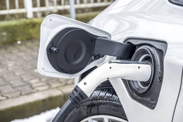 Vista de un coche eléctrico de carga y en el fondo una vista parcial de un coche — Foto de Stock