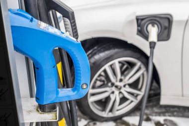 Bir elektrikli araba şarj ve arka planda bir araba kısmi bir görünümü