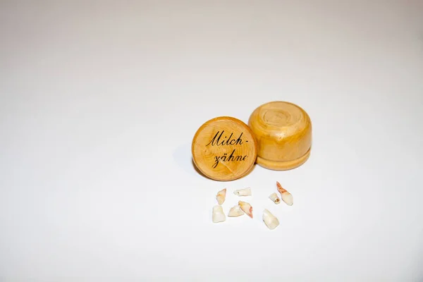 Collection of extracted milk teeth in front of wooden box - Translation: milk teeth