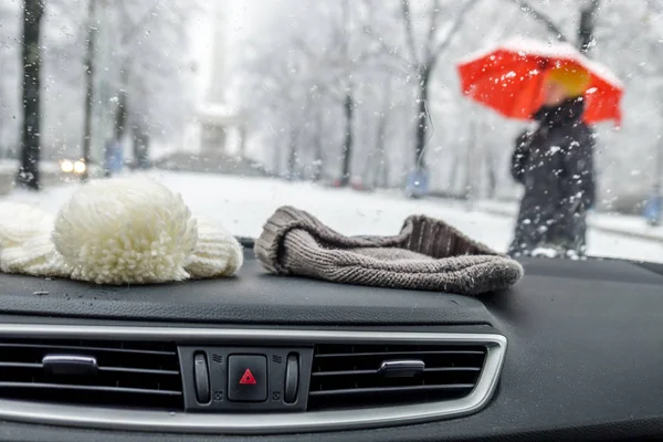 Inverno conceitual tiro de beanies em um carro atrás da janela da frente, enquanto a senhora com guarda-chuva vermelho passa — Fotografia de Stock