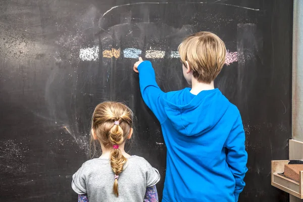 Boy explaining and girl something on the chalkboard — Stock Photo, Image