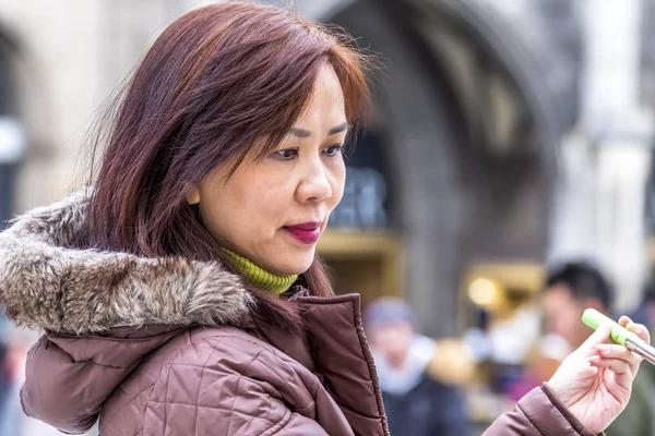 Monachium, Niemcy - 15 luty 2018: Azjatycki dama robienia selfie z jej smartphone — Zdjęcie stockowe